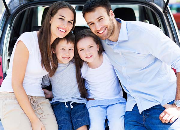 smiling family with mom, dad, and two kids in white and blue clothes