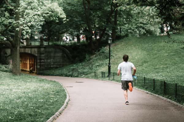 man in white shirt running in a park